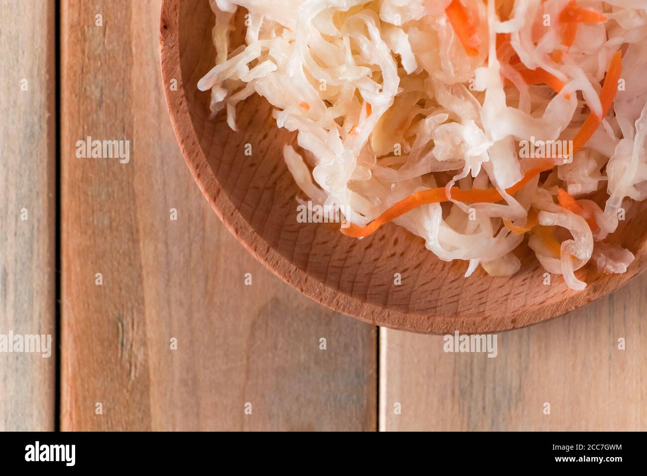 Homemade sauerkraut on a wooden plate. Fermented cabbage with carrot on a light background. Eco food, the trend of healthy eating. Place for your text Stock Photo