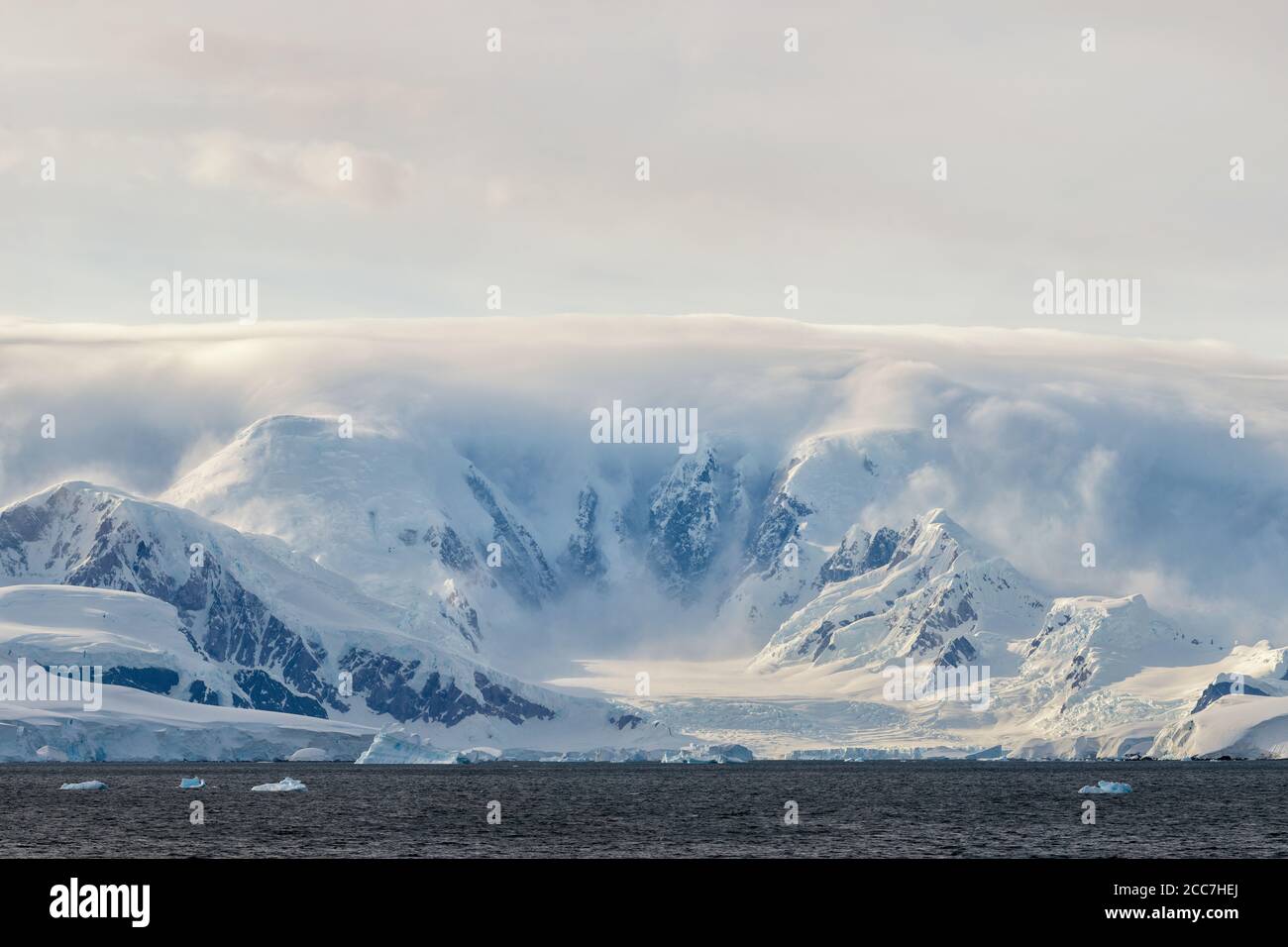 Glacier covered mountains enveloped in clouds in Antarctica. Stock Photo