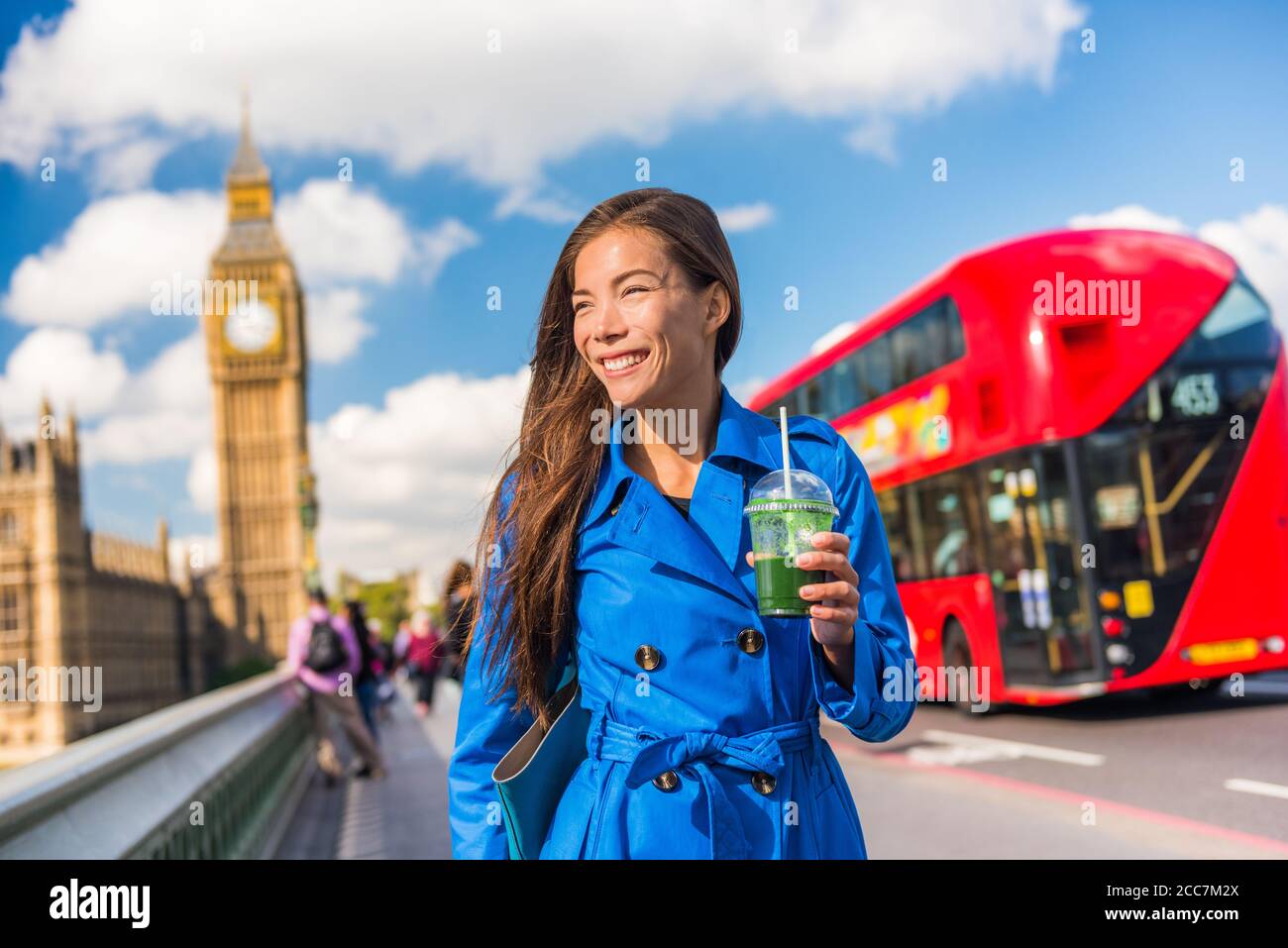 Healthy London urban city business woman drinking green detox smoothie walking on Westminster Bridge with Big Ben, red double decker bus background Stock Photo