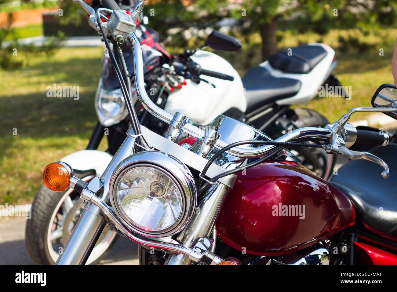 Beautiful burgundy motorcycle in the sun. Chrome steering wheel. Stock Photo