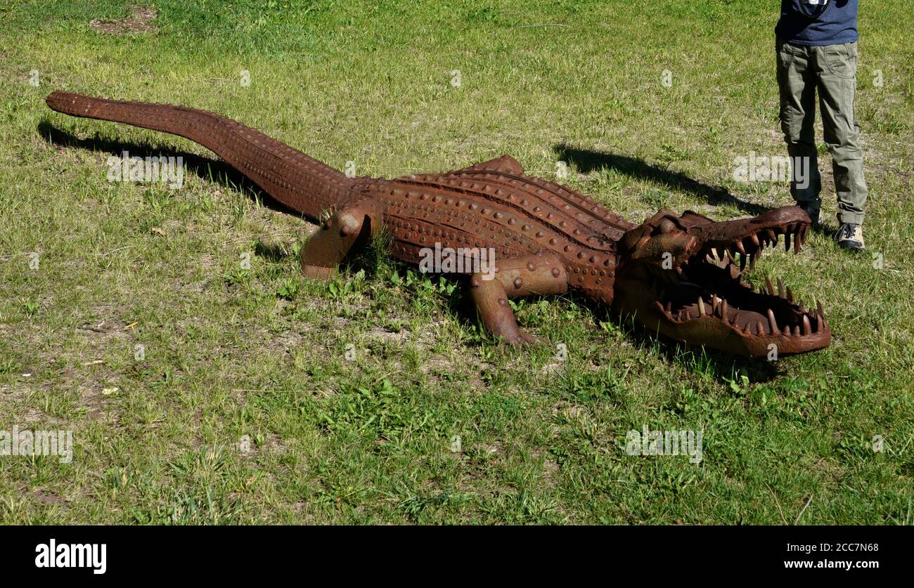 A tourist looks at a lifesize metal sculpture of an alligator by Joe  Barrington on display outside an art gallery in Tesuque, New Mexico USA  Stock Photo - Alamy