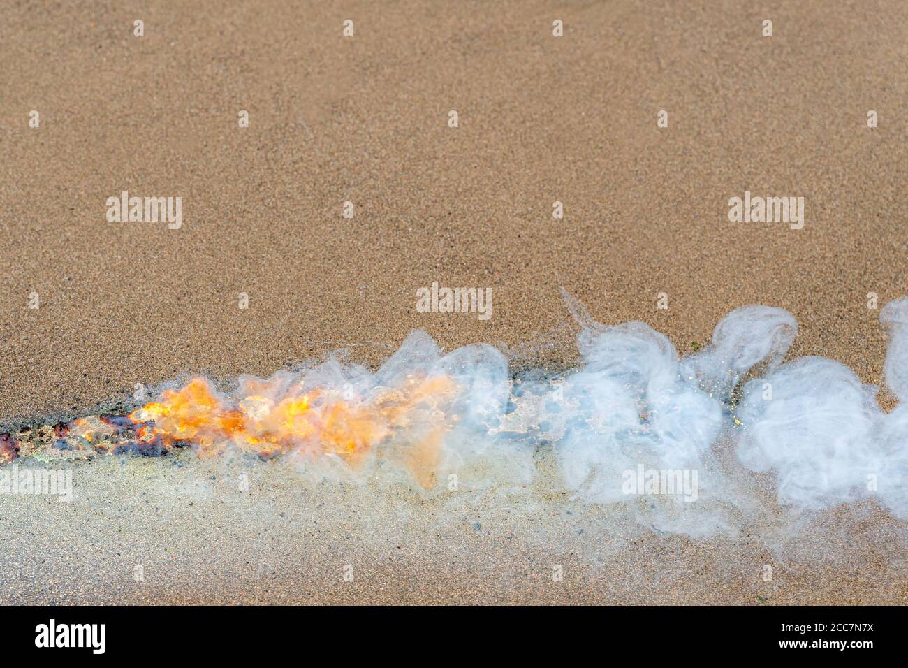 Line of gunpowder burning on sand. The bright orange fire burns