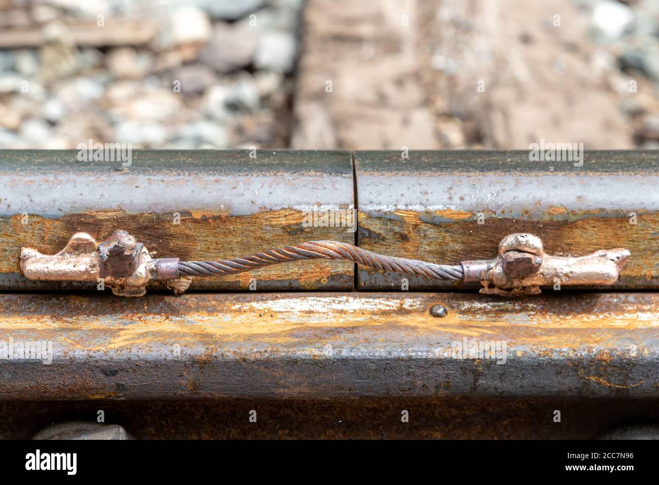A closeup of train track with a small cable welded to connect two rails. This is for the signal