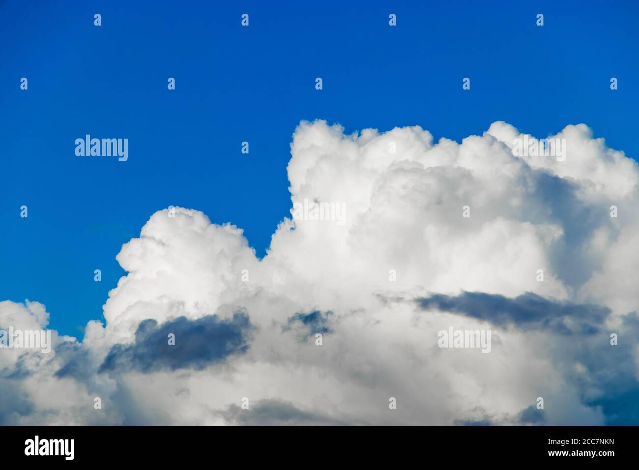 White fluffy cumulus clouds against a clear blue sky. Top view from the plane. Background for design. Stock Photo
