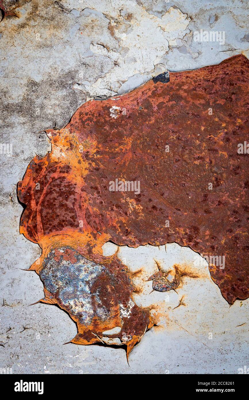 Abstract view of chipped lead paint on badly rusted metal surface; blue, orange, and red colors featured Stock Photo
