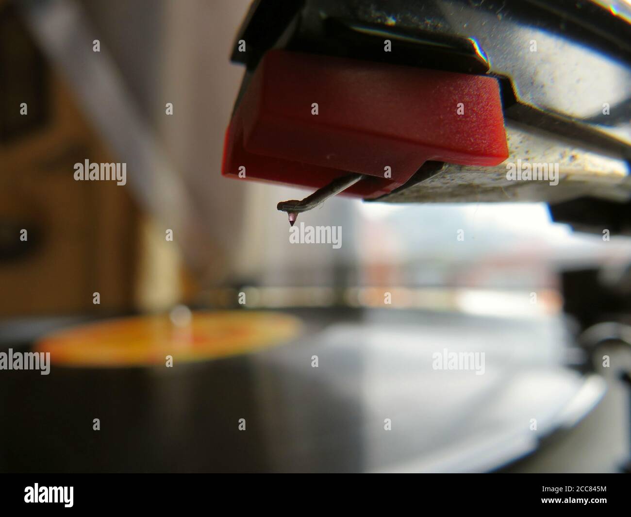 Close up of record player stylus and pick up with vinyl record soft focused in background Stock Photo