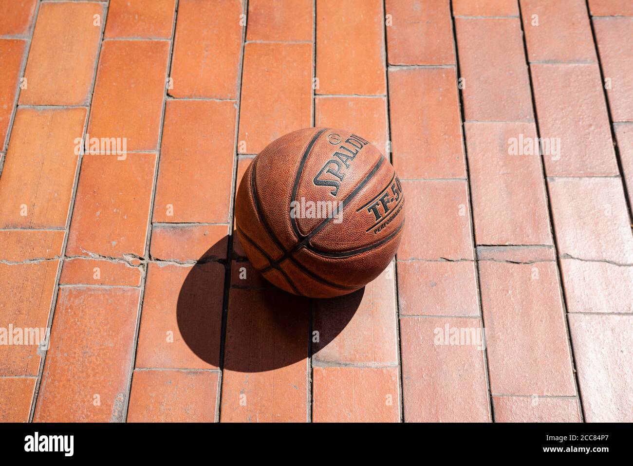 Basketball on terracotta tiles on a sunny day. Stock Photo