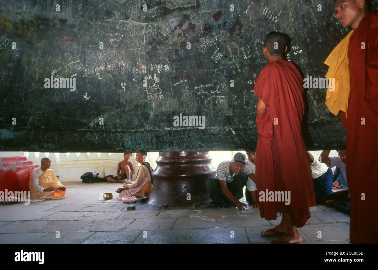 Burma / Myanmar: Buddhist monks inspect the inside of the Mingun Bell in Sagaing Division, Burma. The Mingun Bell is a giant bell located in Mingun, on the western bank of the Irrawaddy River, Sagaing Region, Myanmar. It was the heaviest functioning bell in the world at several times in history. The weight of the bell is 90,718 kg or 199,999 pounds. The bell is uncracked and in good ringing condition. Casting of the bell started in 1808 and was finished by 1810. King Bodawpaya (r. 1782–1819) had this gigantic bell cast to go with his huge stupa, Mingun Pahtodawgyi. Stock Photo