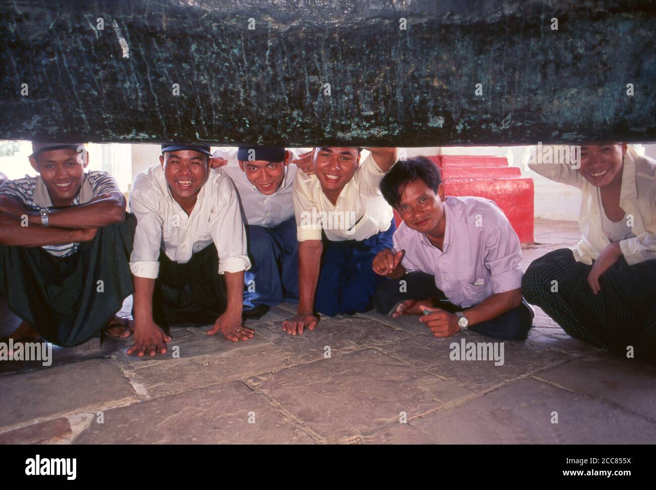 Burma / Myanmar: A group of young men looking inside the giant Mingun Bell in Sagaing Division, Burma. The Mingun Bell is a giant bell located in Mingun, on the western bank of the Irrawaddy River, Sagaing Region, Myanmar. It was the heaviest functioning bell in the world at several times in history. The weight of the bell is 90,718 kg or 199,999 pounds. The bell is uncracked and in good ringing condition. Casting of the bell started in 1808 and was finished by 1810. King Bodawpaya (r. 1782–1819) had this gigantic bell cast to go with his huge stupa, Mingun Pahtodawgyi. Stock Photo