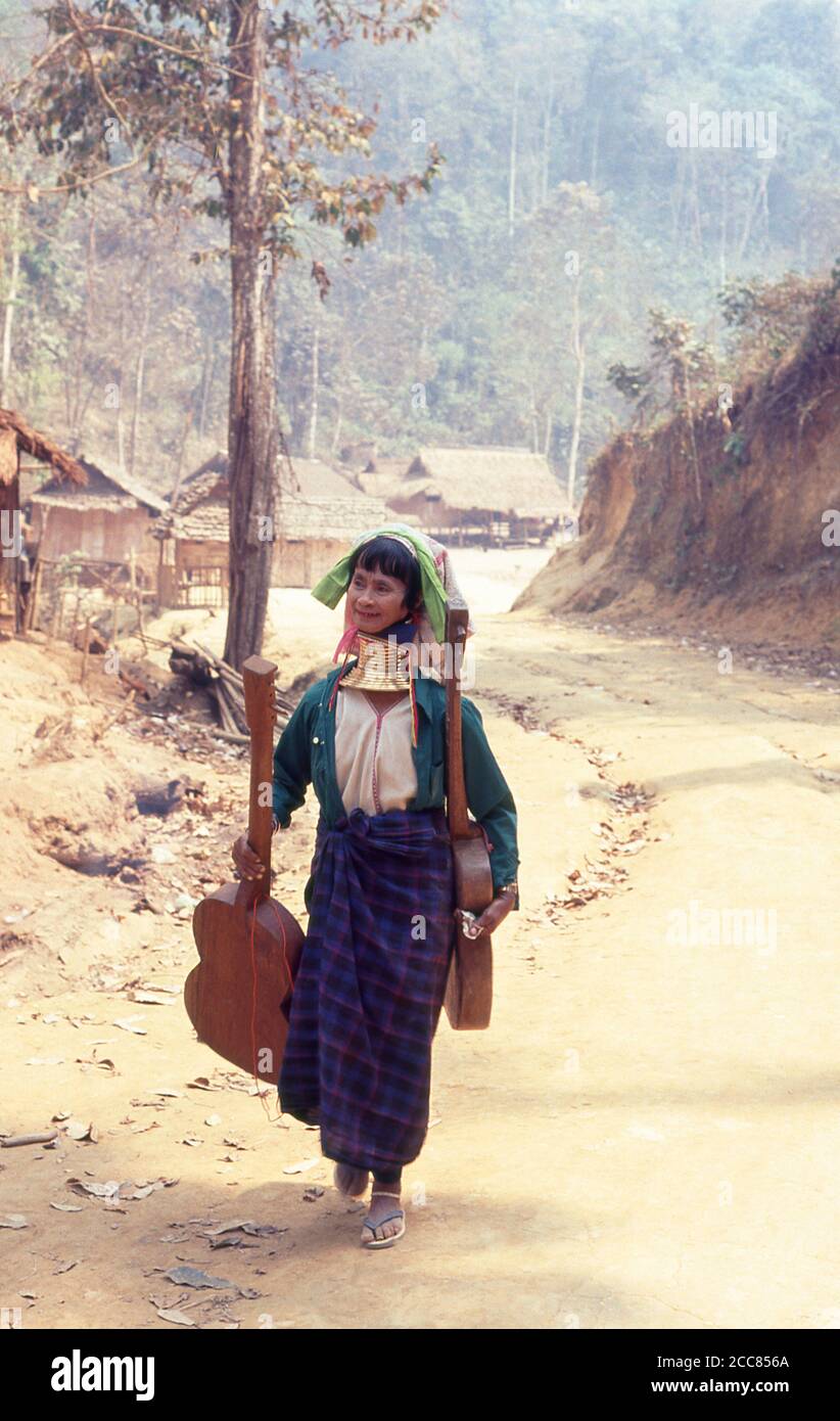 Thailand: Padaung (Long Neck Karen) woman carrying homemade guitars, village near Mae Hong Son, northern Thailand. The Padaung or Kayan Lahwi or Long Necked Karen are a subgroup of the Kayan, a mix of Lawi, Kayan and several other tribes. Kayan are a subgroup of the Red Karen (Karenni) people, a Tibeto-Burman ethnic minority of Burma (Myanmar). Stock Photo