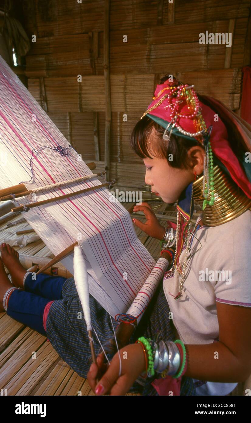 Thailand: Padaung (Long Neck Karen) girl weaving, Chiang Mai Province, northern Thailand. The Padaung or Kayan Lahwi or Long Necked Karen are a subgroup of the Kayan, a mix of Lawi, Kayan and several other tribes. Kayan are a subgroup of the Red Karen (Karenni) people, a Tibeto-Burman ethnic minority of Burma (Myanmar). Stock Photo