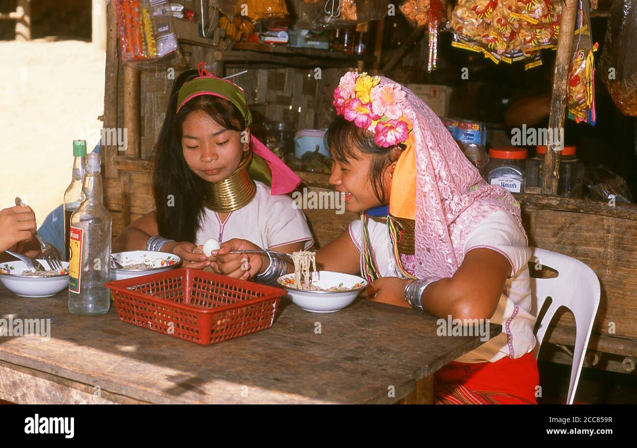 Thailand: Padaung (Long Neck Karen) women eating noodles in a village near Mae Hong Son, northern Thailand. The Padaung or Kayan Lahwi or Long Necked Karen are a subgroup of the Kayan, a mix of Lawi, Kayan and several other tribes. Kayan are a subgroup of the Red Karen (Karenni) people, a Tibeto-Burman ethnic minority of Burma (Myanmar). Stock Photo