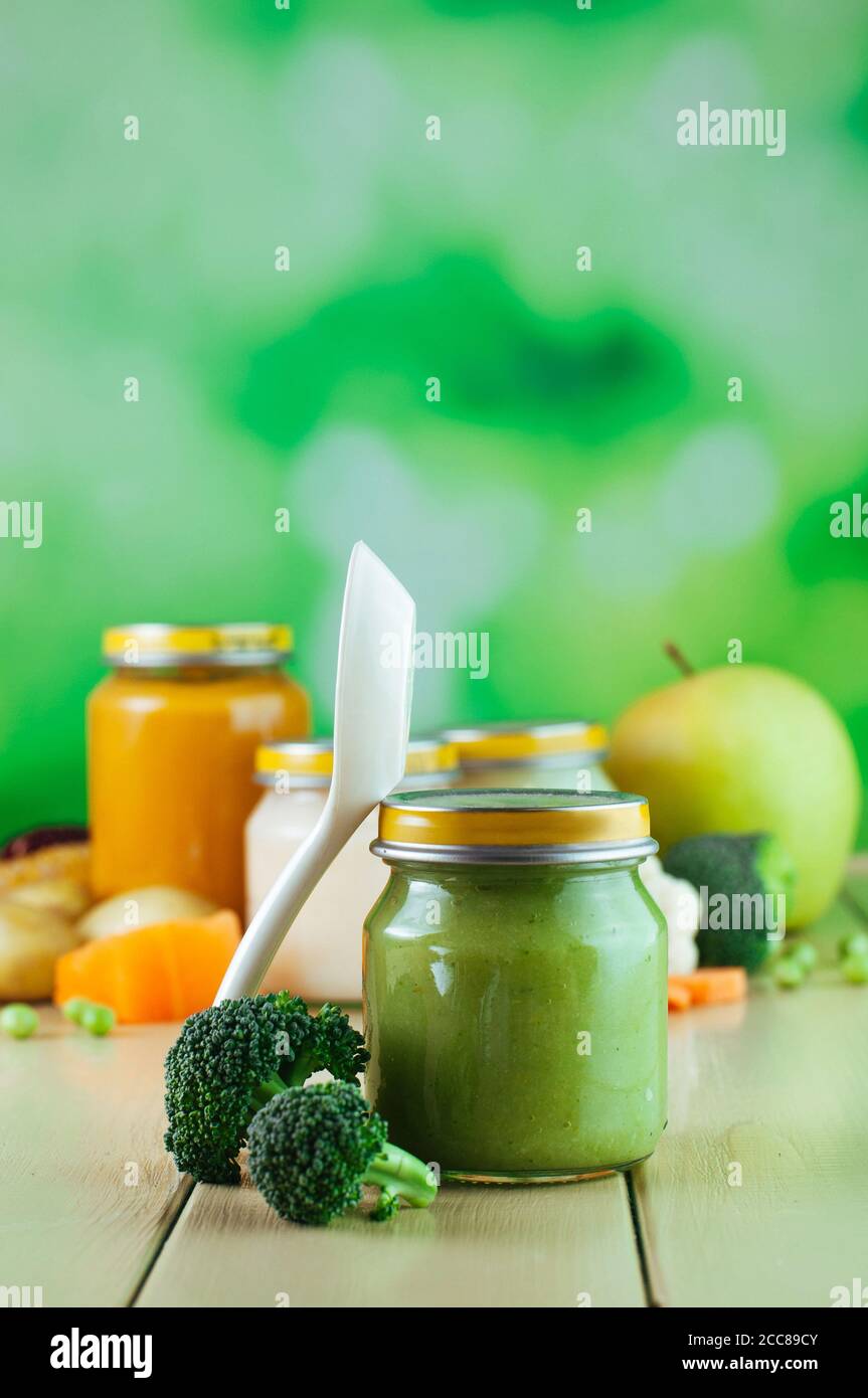 Jar with broccoli puree with spoon on the light wooden background Stock Photo