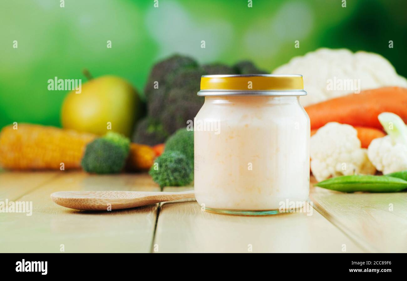 Jar with puree with spoon near fresh fruits and vegetables Stock Photo