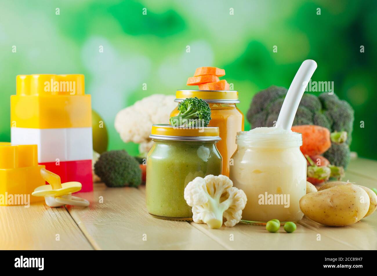 Jars with puree with spoon near fresh fruits and vegetables Stock Photo