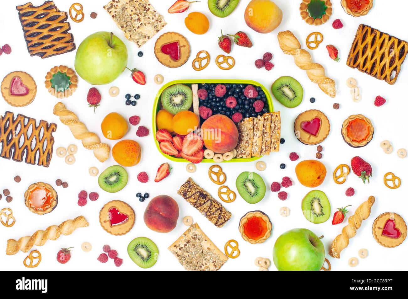 Lunch box and variety of fruits, berries and crunches on white