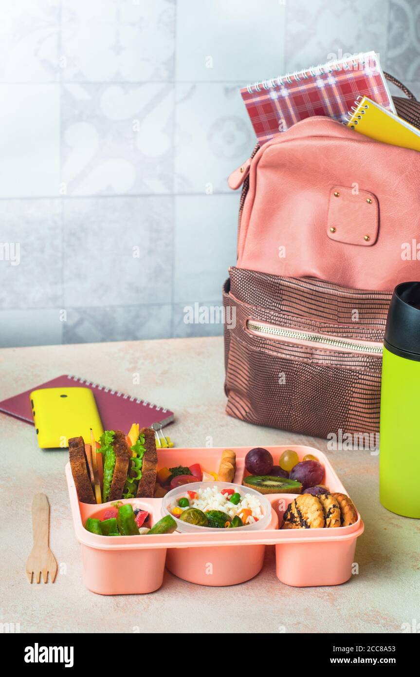 https://c8.alamy.com/comp/2CC8A53/lunch-box-with-sandwiches-vegetable-salad-and-fresh-fruits-and-rice-on-the-table-near-school-backpack-2CC8A53.jpg