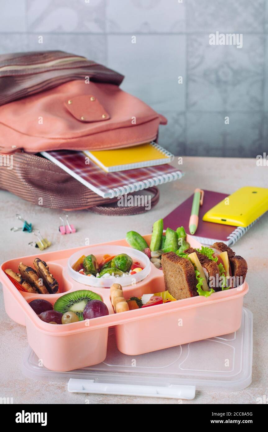 Lunch box with sandwiches, fresh fruits and vegetables on the table ...