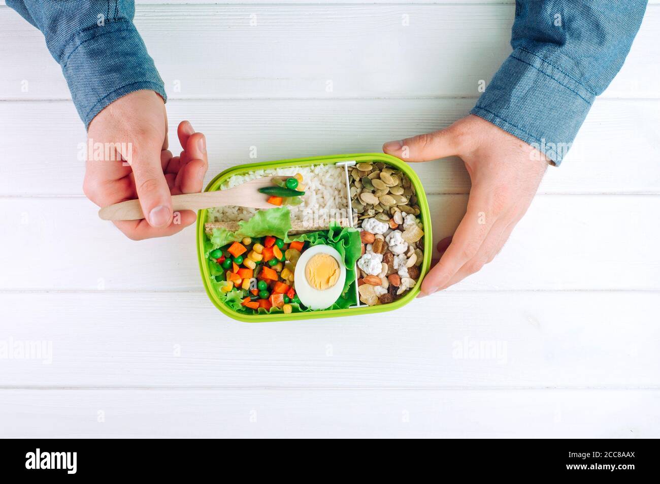 Males hands holding lunch box to eat rice, mixed vegetables, boiled egg Stock Photo