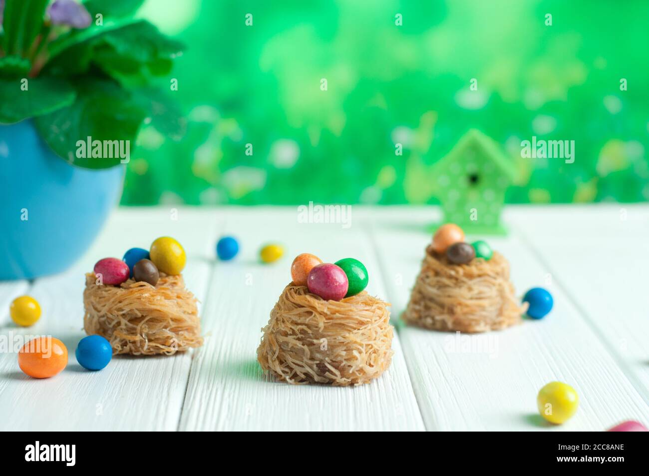 Painted chocolate eggs in sweet nests over white wooden background Stock Photo