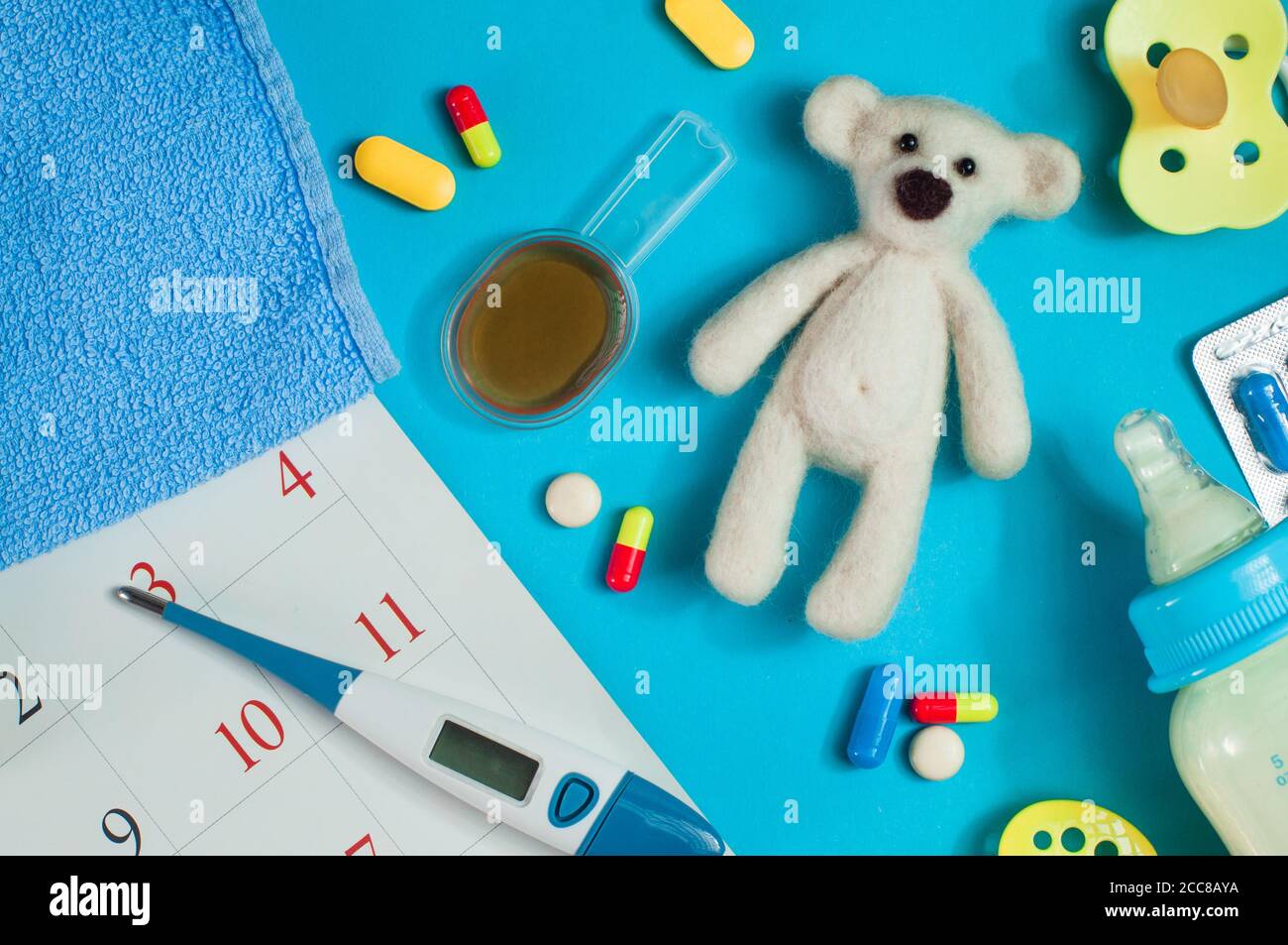 Pills, milk bottle and electronic thermometer near calendar page Stock Photo