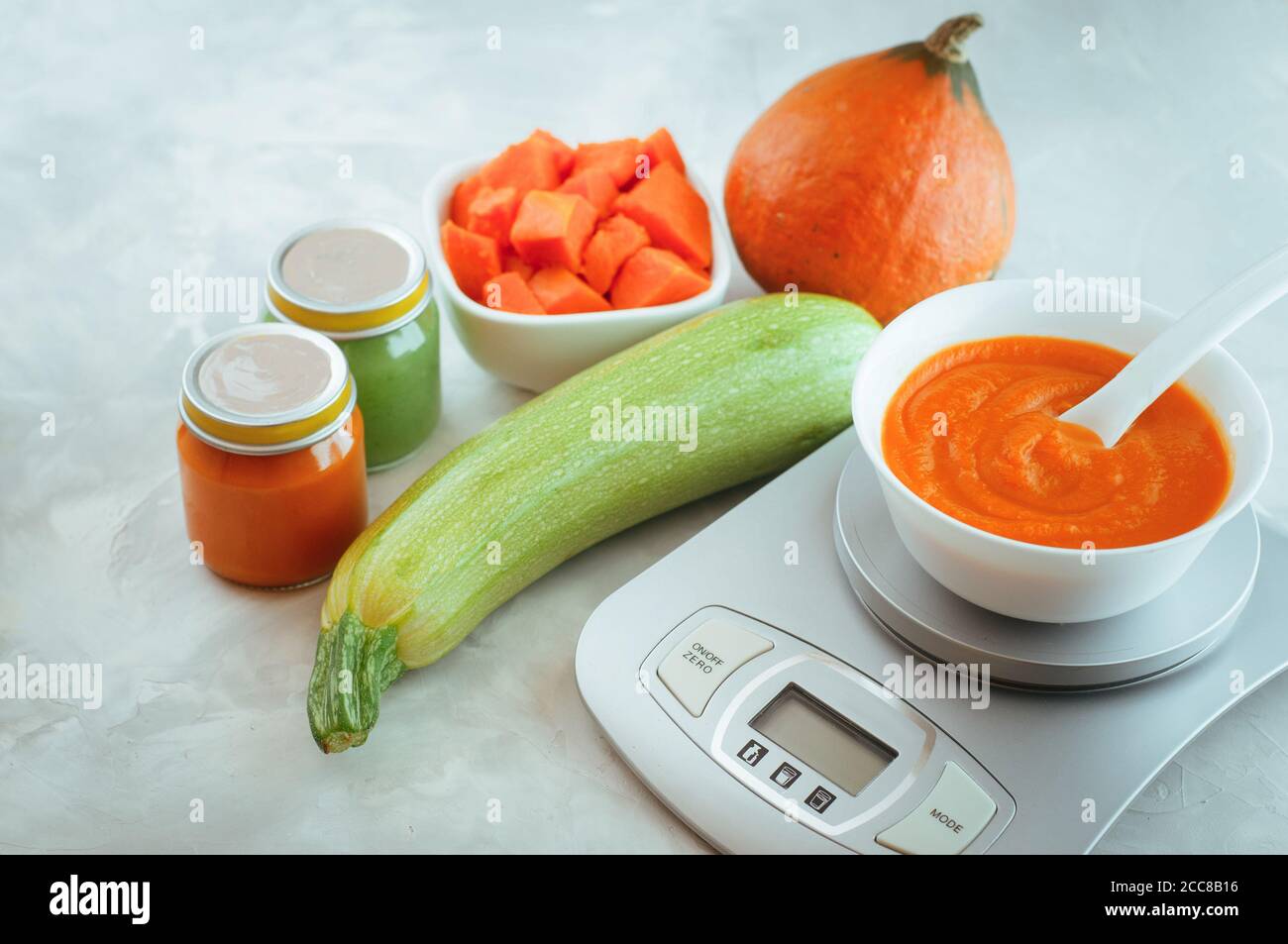 Plate with pumpkin puree for baby first lure on kitchen scale Stock Photo