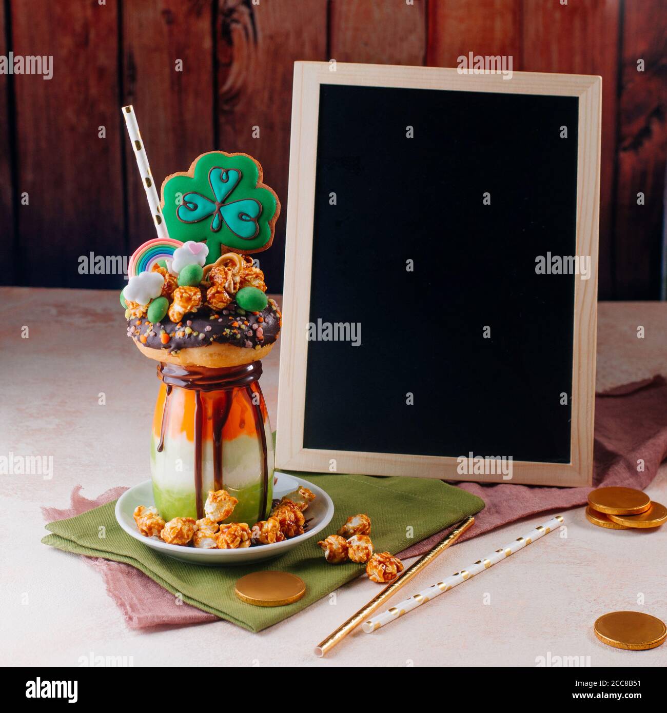 Saint Patrick freak shake topping with clover cookie near black board on beige background Stock Photo