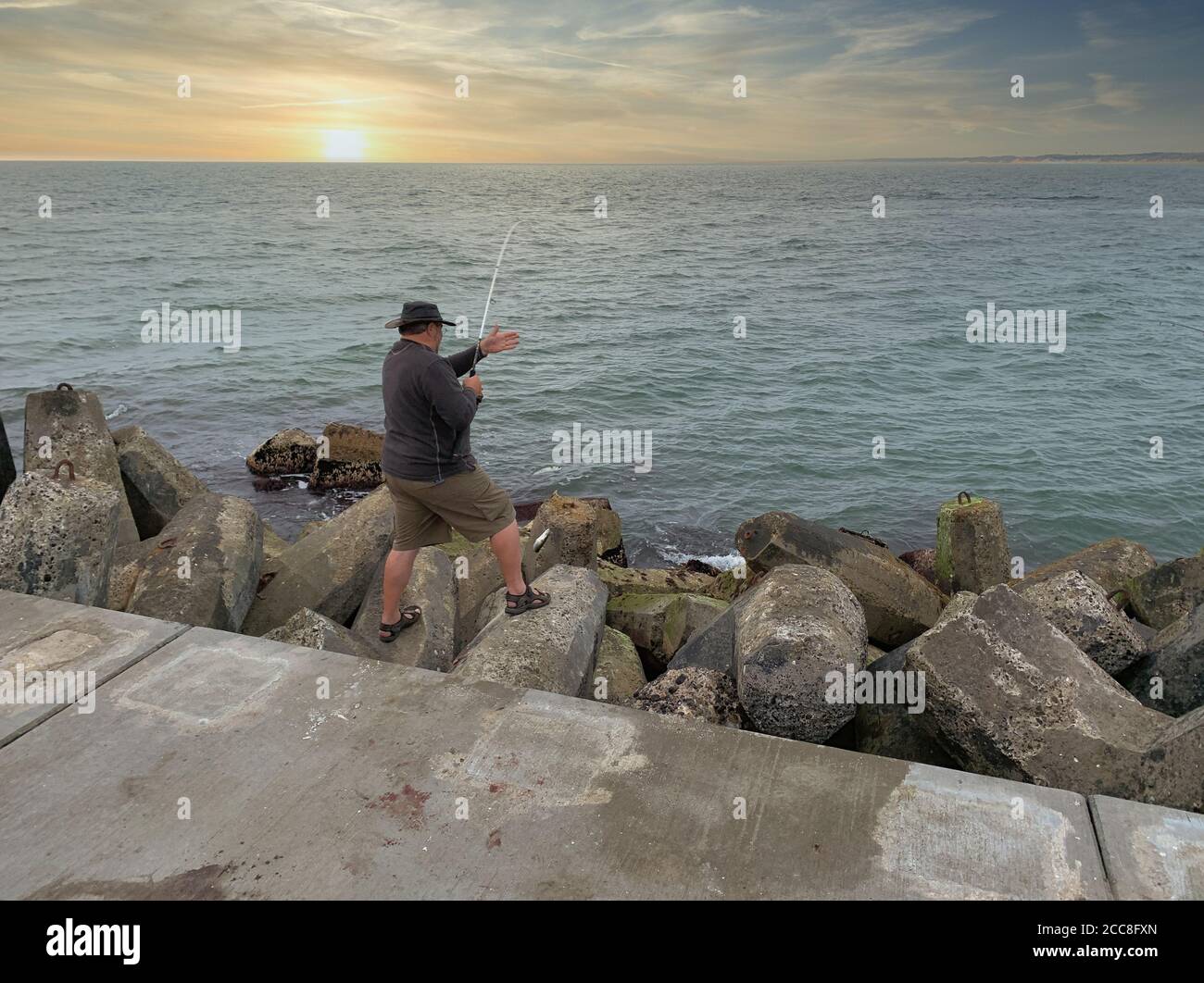 Fisherman fishing in the ocean under the sunset Stock Photo - Alamy
