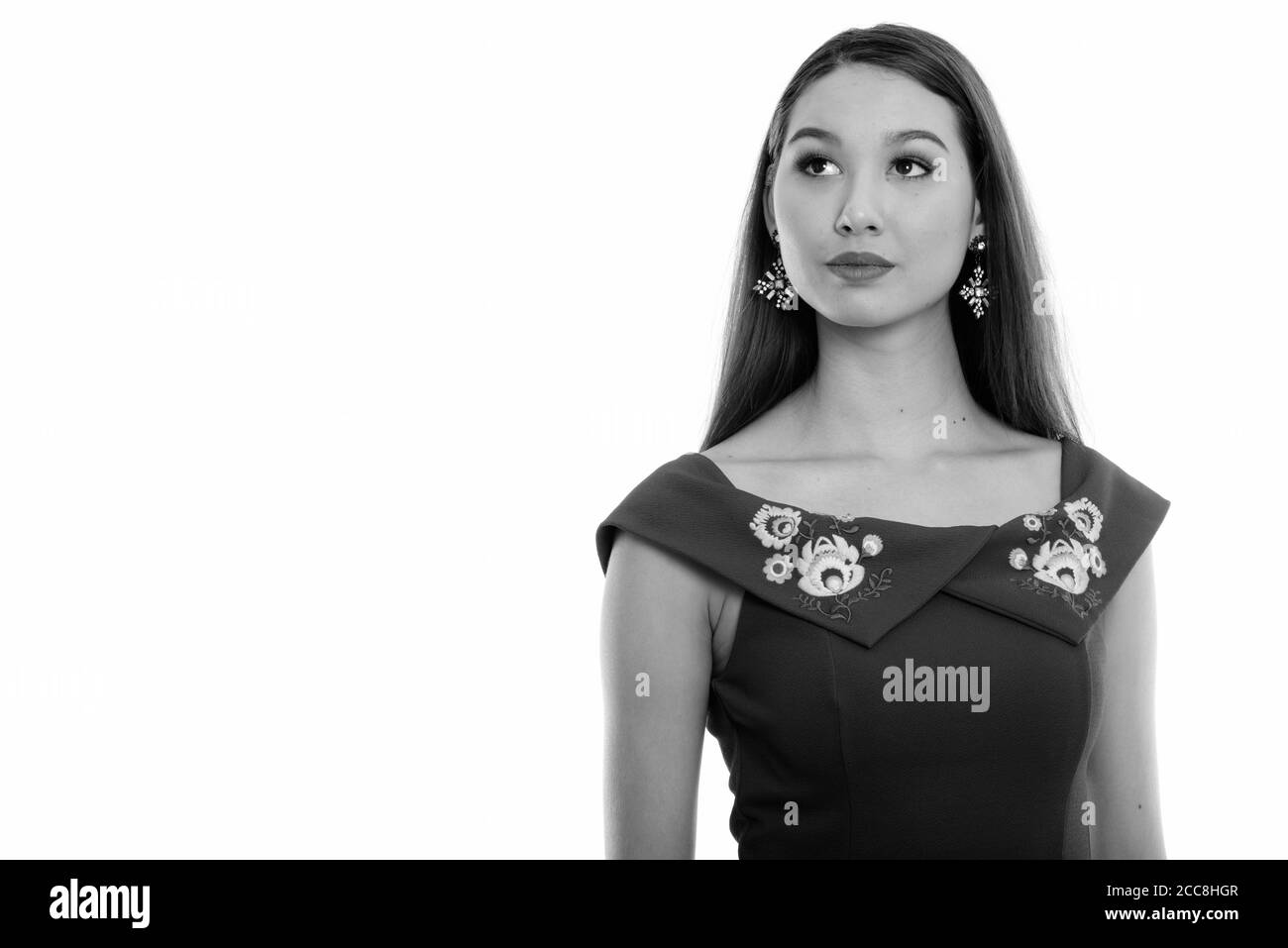Studio shot of young beautiful Asian woman thinking while looking up ...