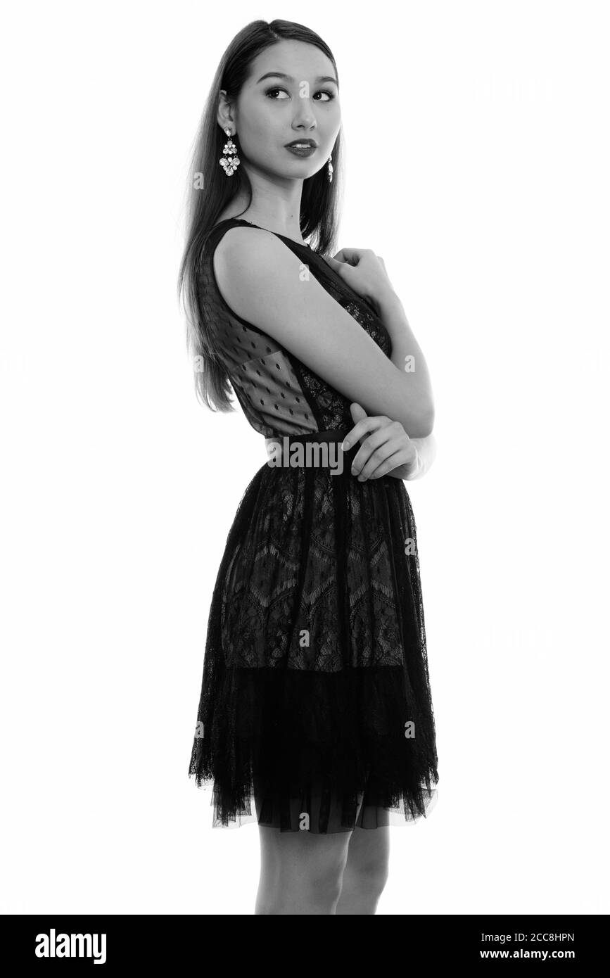 Studio shot of young beautiful Asian woman standing and thinking while ...