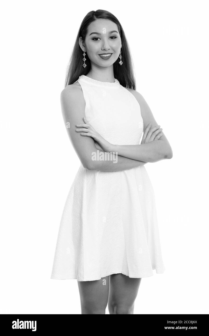 Studio shot of young happy beautiful Asian woman smiling and standing ...