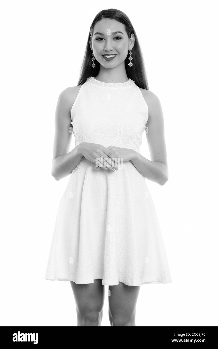 Studio shot of young happy beautiful Asian woman smiling and standing ...