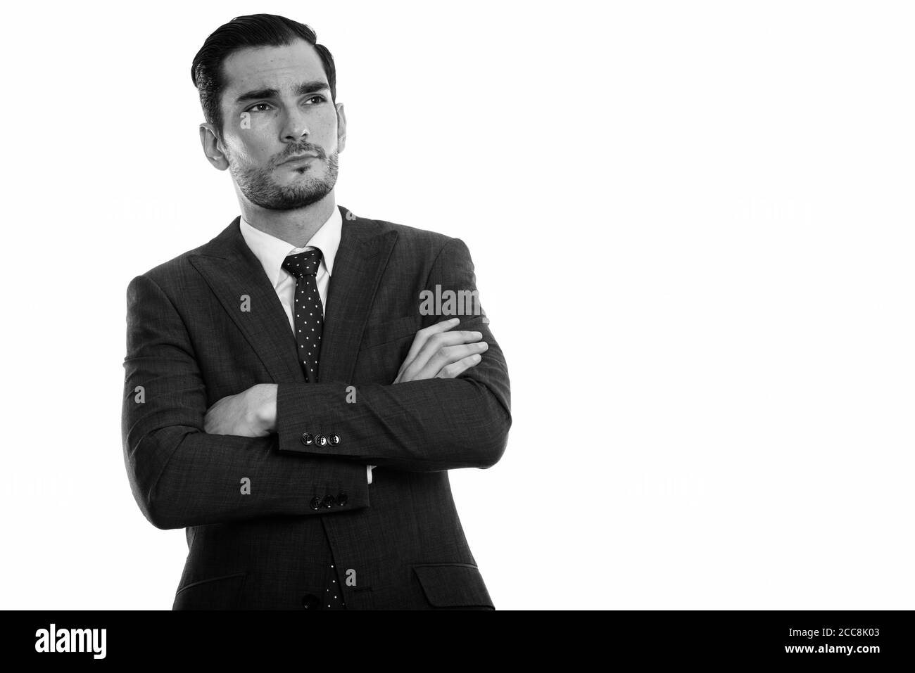 Studio shot of young handsome businessman thinking with arms crossed ...