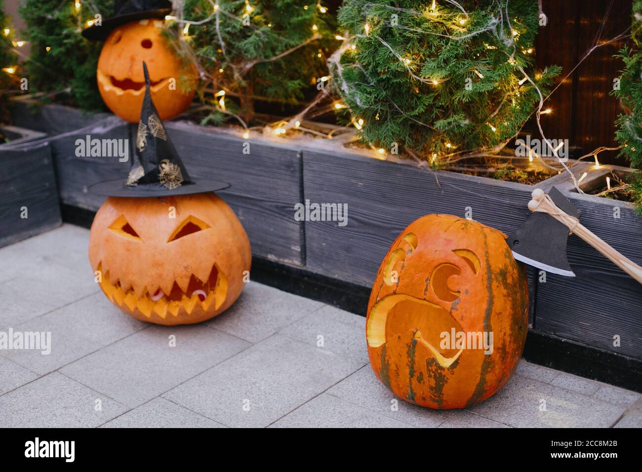 Halloween street decor. Carved pumpkins with scary face, witch hat and ...
