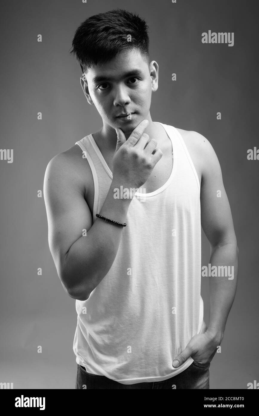 Young handsome Asian man wearing tank top against gray background Stock Photo