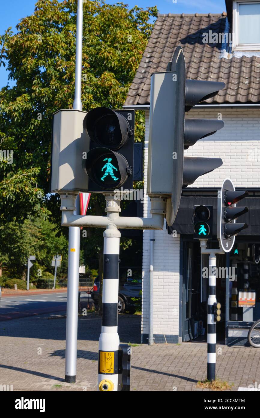 Green pedestrian light with a walking or waiting happy girl with ponytail at crossroads in the Netherlands. The name of the girl is Sofie and she Stock Photo