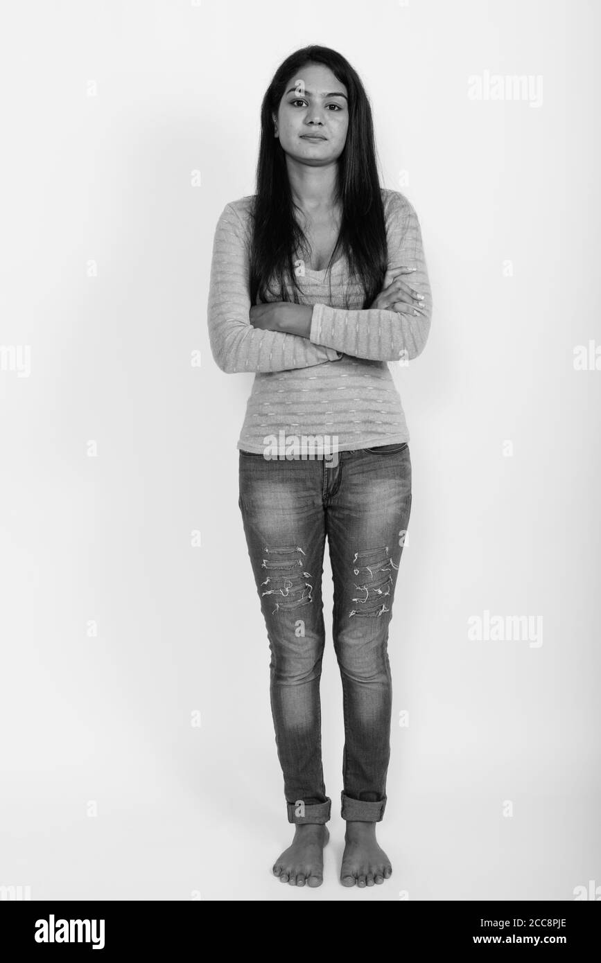 Full body shot of young Indian woman standing with arms crossed barefoot against white background Stock Photo