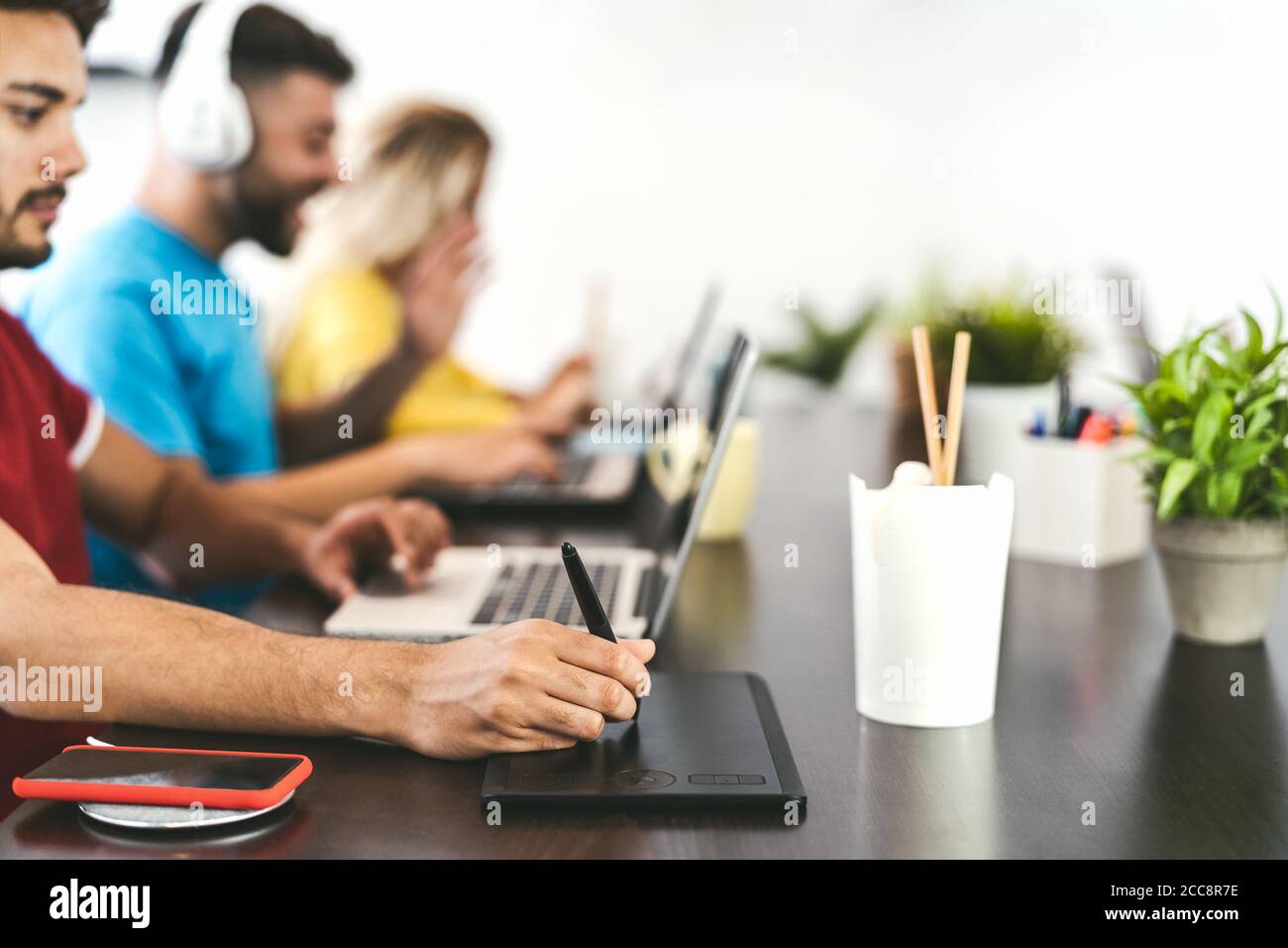 Young friends working together inside co-working creative space - Millennial people doing startup strategy in modern office Stock Photo