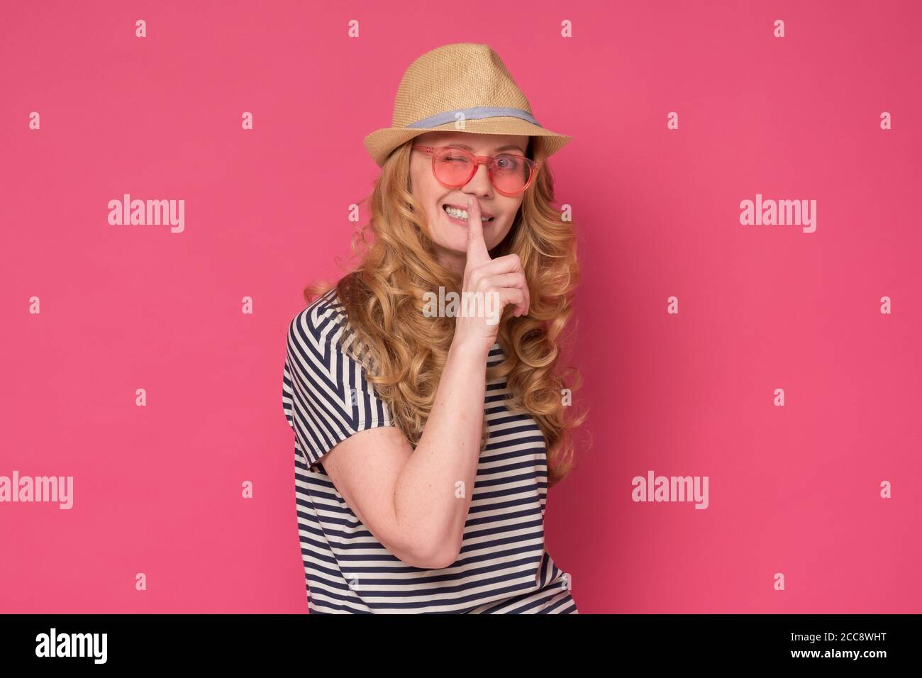 Beautiful mature woman wear sunglasses and hat showing silent gesture. Stock Photo