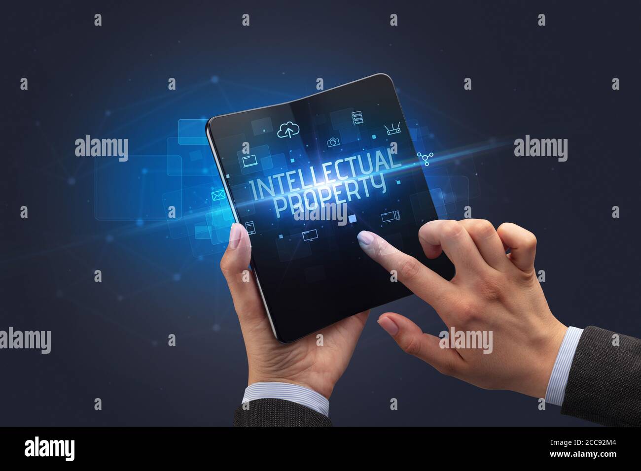 Businessman holding a foldable smartphone with INTELLECTUAL PROPERTY inscription, cyber security concept Stock Photo