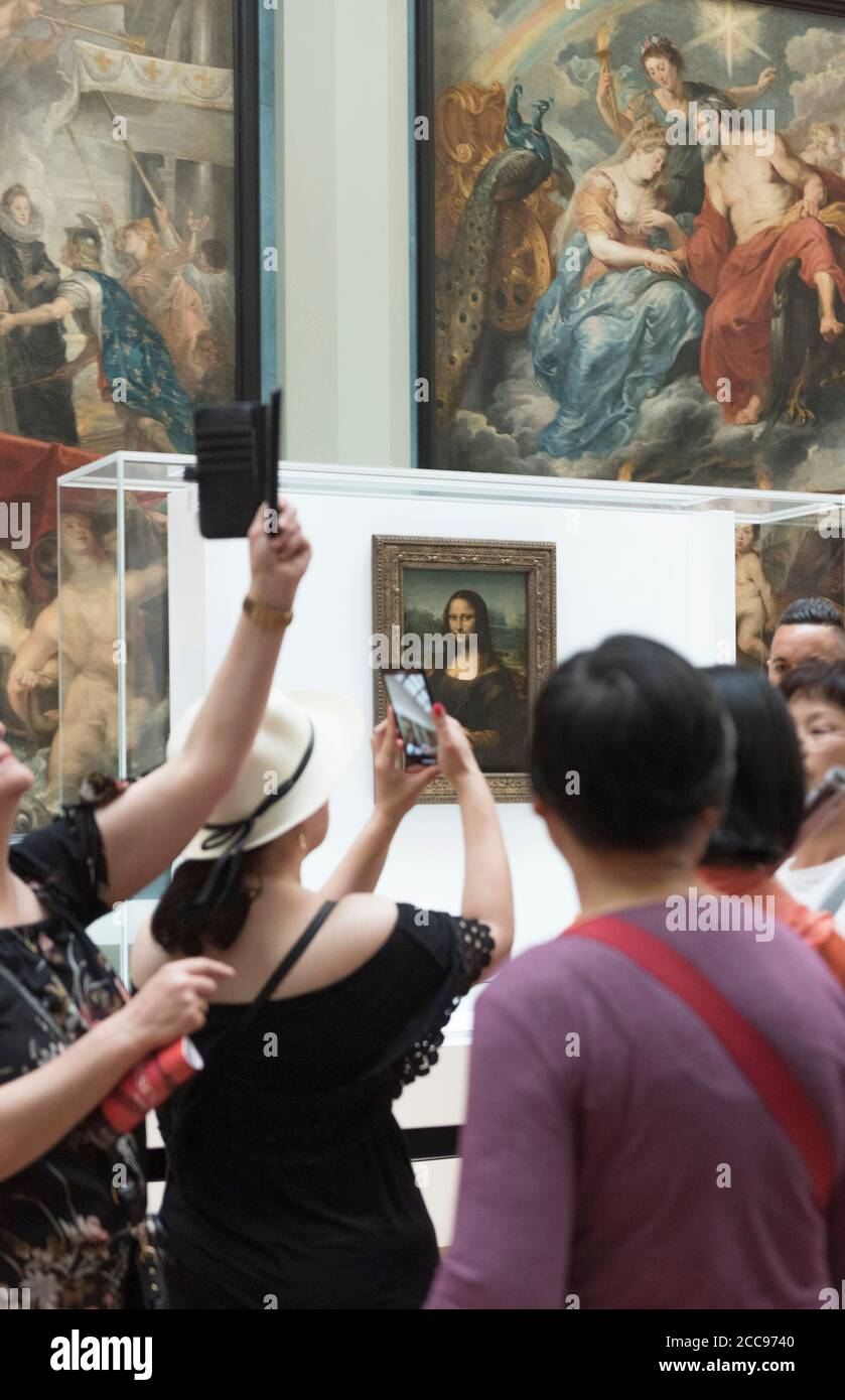 The Mona Lisa, by Leonardo da Vinci, at the Louvre Museum in Paris tourists taking pictures of the painting with smartphones Stock Photo