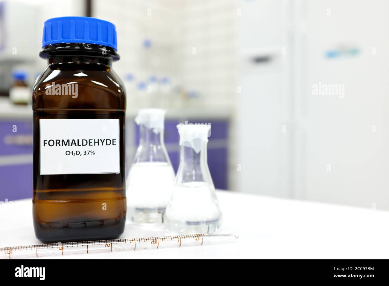 Selective focus of formaldehyde or formalin in brown amber glass bottle inside a laboratory. Blurred background with copy space. Stock Photo
