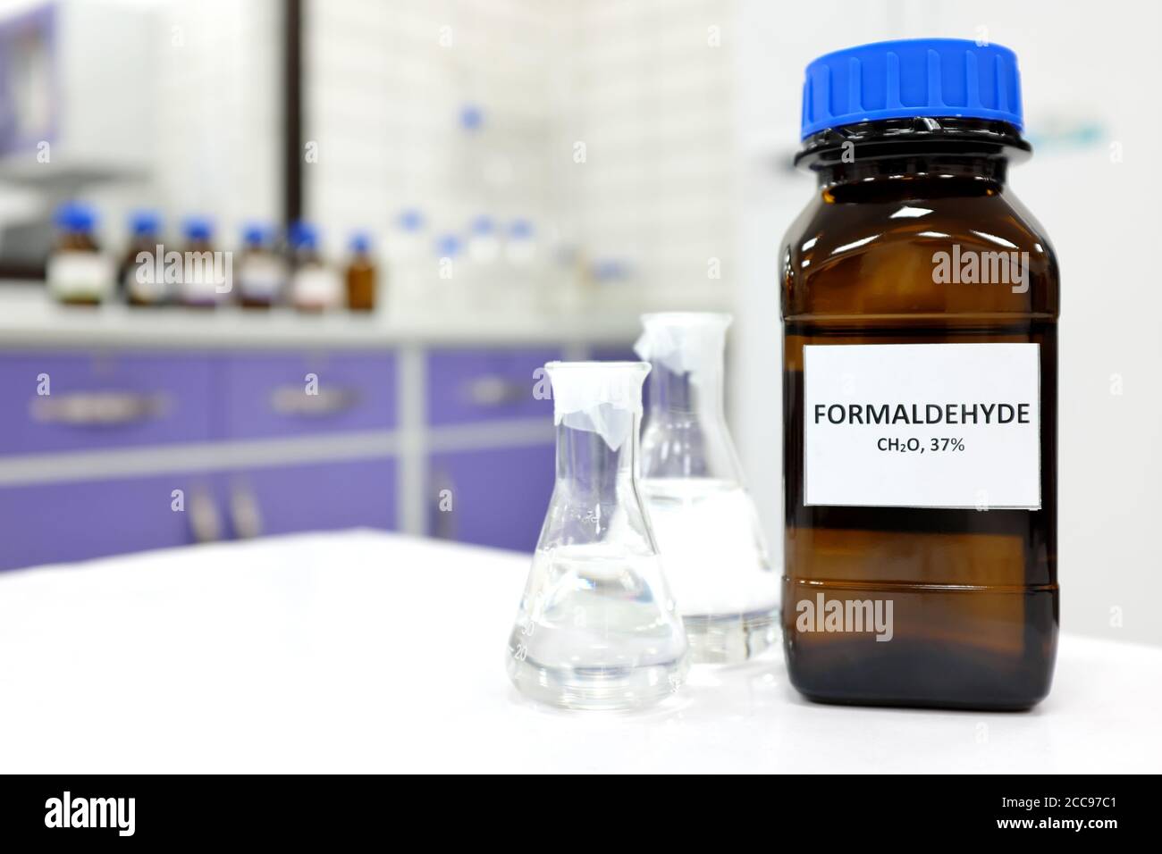 Selective focus of formaldehyde or formalin in brown amber glass bottle inside a laboratory. Blurred background with copy space. Stock Photo