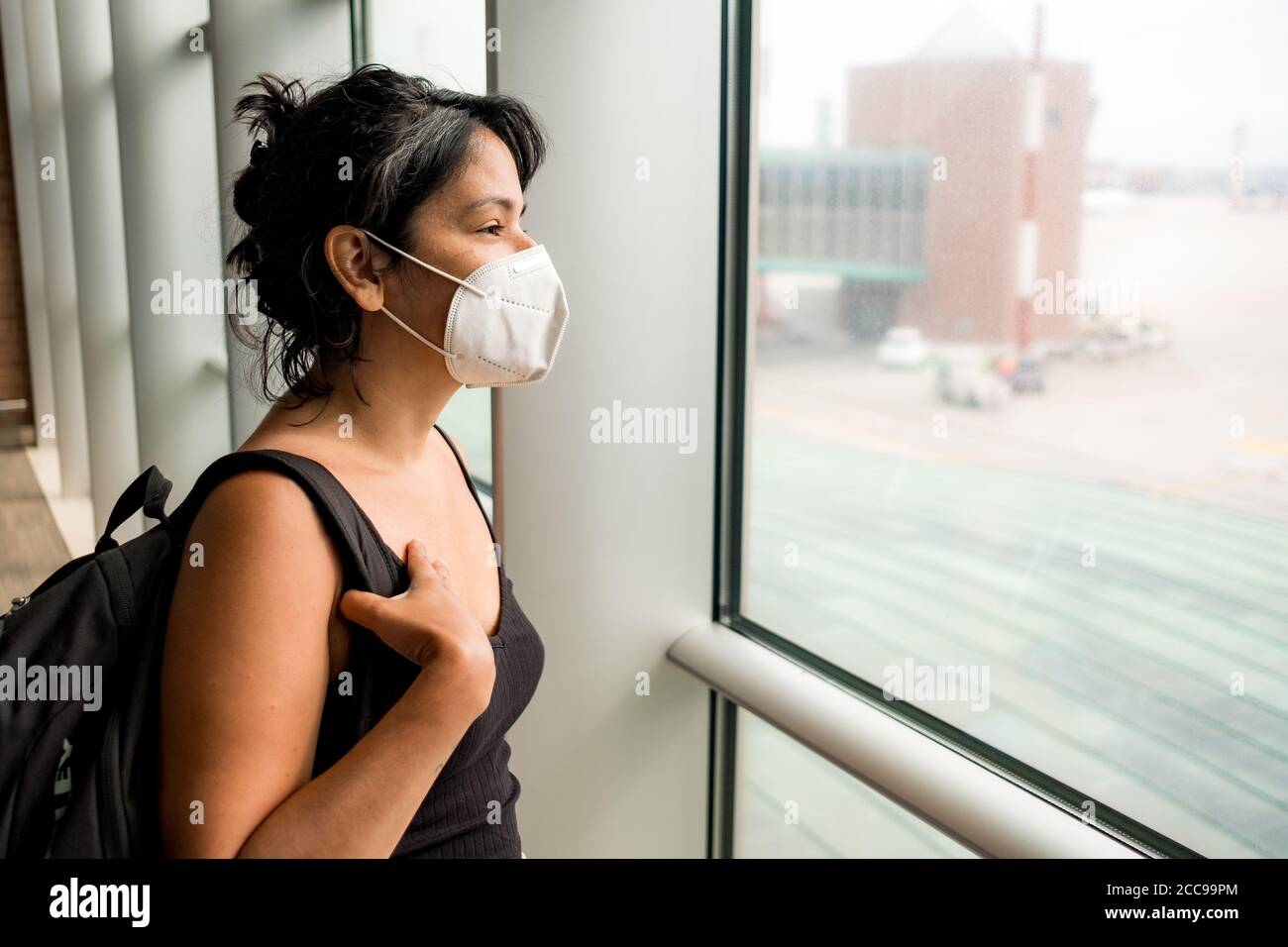 worried young woman at airport wearing face mask, going on vacation and traveling during the covid19 pandemic. Corona virus has caused a crisis in the Stock Photo