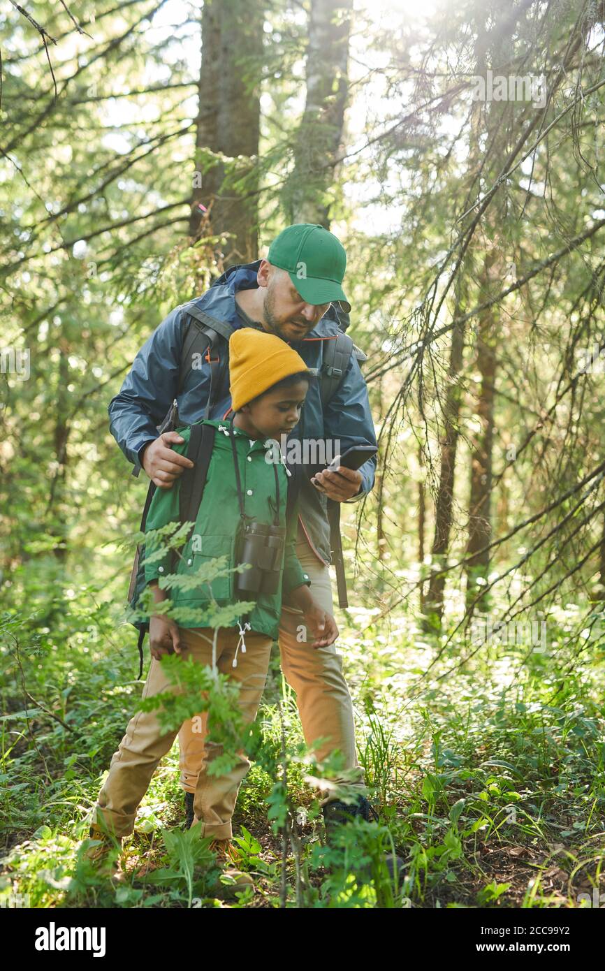 Father and son using mobile phone as a compass while walking in the forest Stock Photo