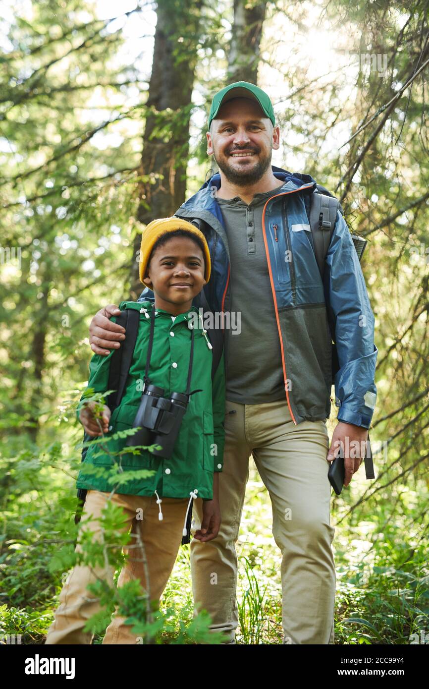 Portrait of happy father standing together with his son in the forest ...