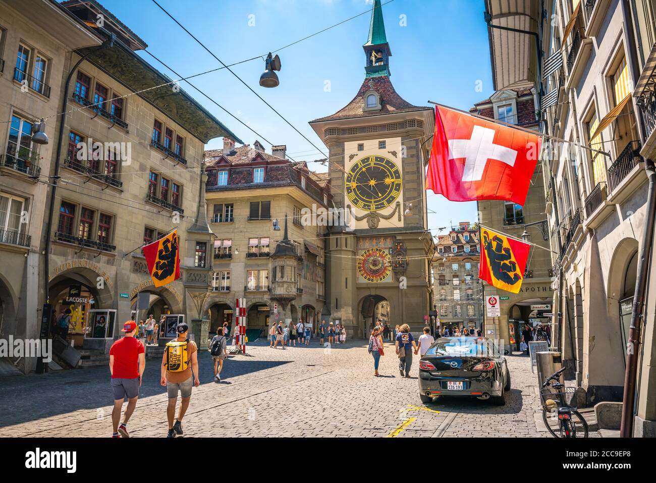Bern Switzerland , 27 June 2020 : Old street view with tourists flags and Zytglogge clock tower in Kramgasse street in Bern old town Switzerland Stock Photo