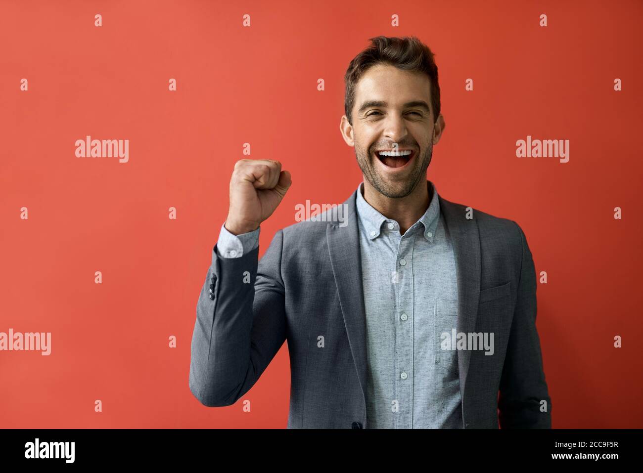 Ecstatic businessman cheering in front of a red background Stock Photo