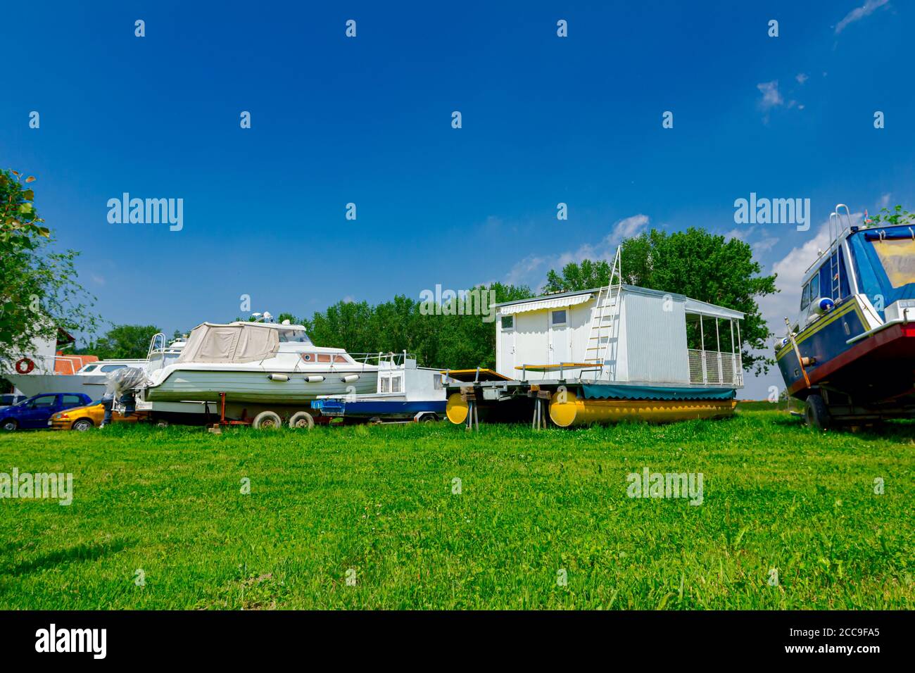 Motor boats on the trailers are dry docked on the grass field. Stock Photo