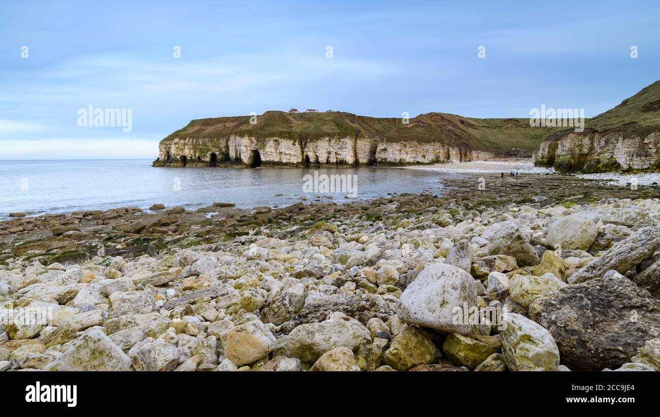Scenic cove, rocky beach, high rugged chalk cliffs, calm sea, blue summer evening sky - Thornwick Bay, Flamborough, East Yorkshire Coast, England, UK. Stock Photo